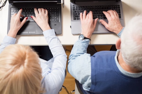 Close-up of older married couple working together on laptops